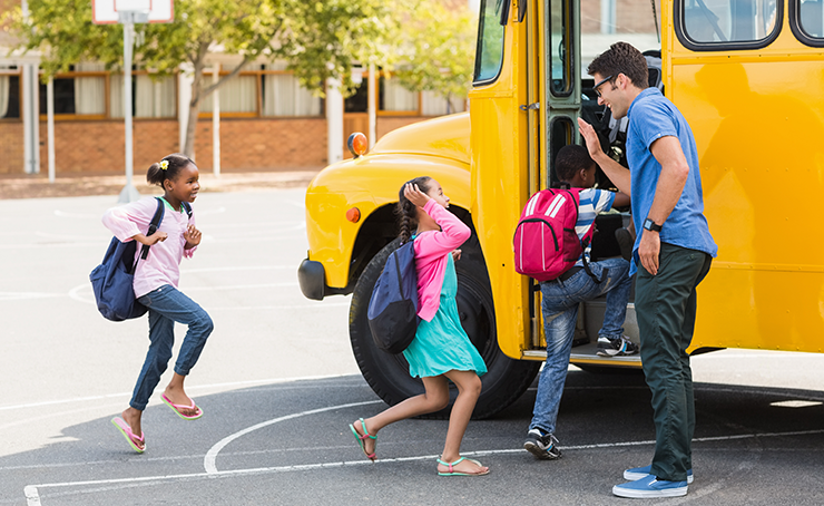 A bus driver high fiving students as they board a bus