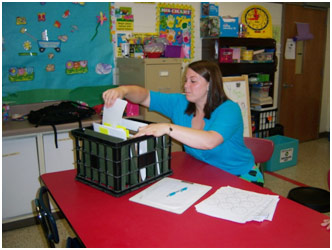 A teacher at a table sorting students' work