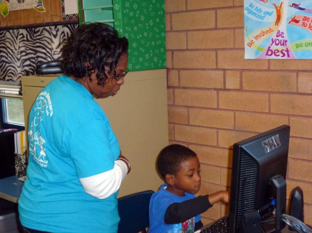 Female teacher directing young male student using a computer